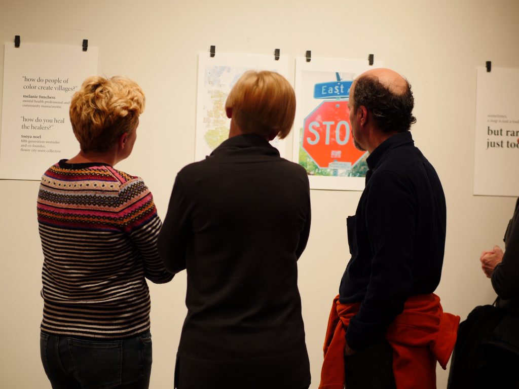 three gallery visitors examine prints